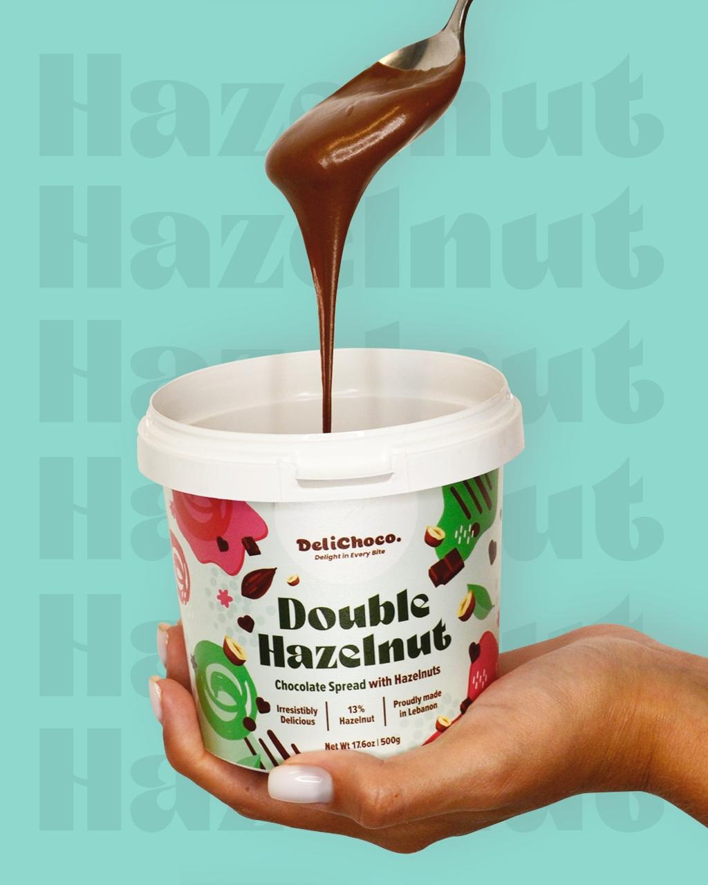Hand holding a container of Double Hazelnut spread with chocolate being poured over it, on a teal background.